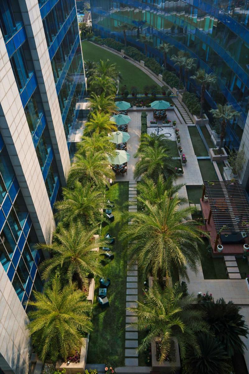 an overhead view of a courtyard with palm trees in a building at The Leela Ambience Gurugram Hotel & Residences - The Luxury Urban Sanctuary in Gurgaon