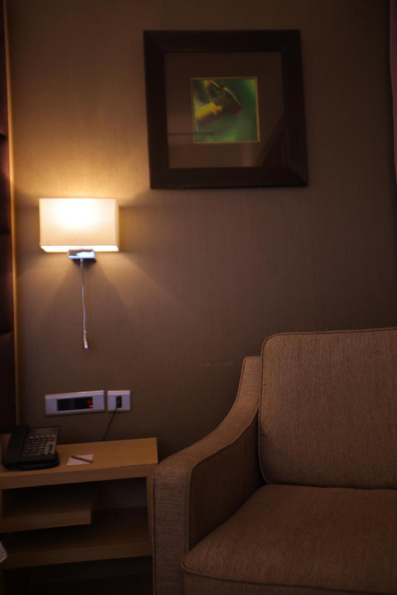 a room with a couch and a lamp on a wall at Novotel Hyderabad Airport in Hyderabad