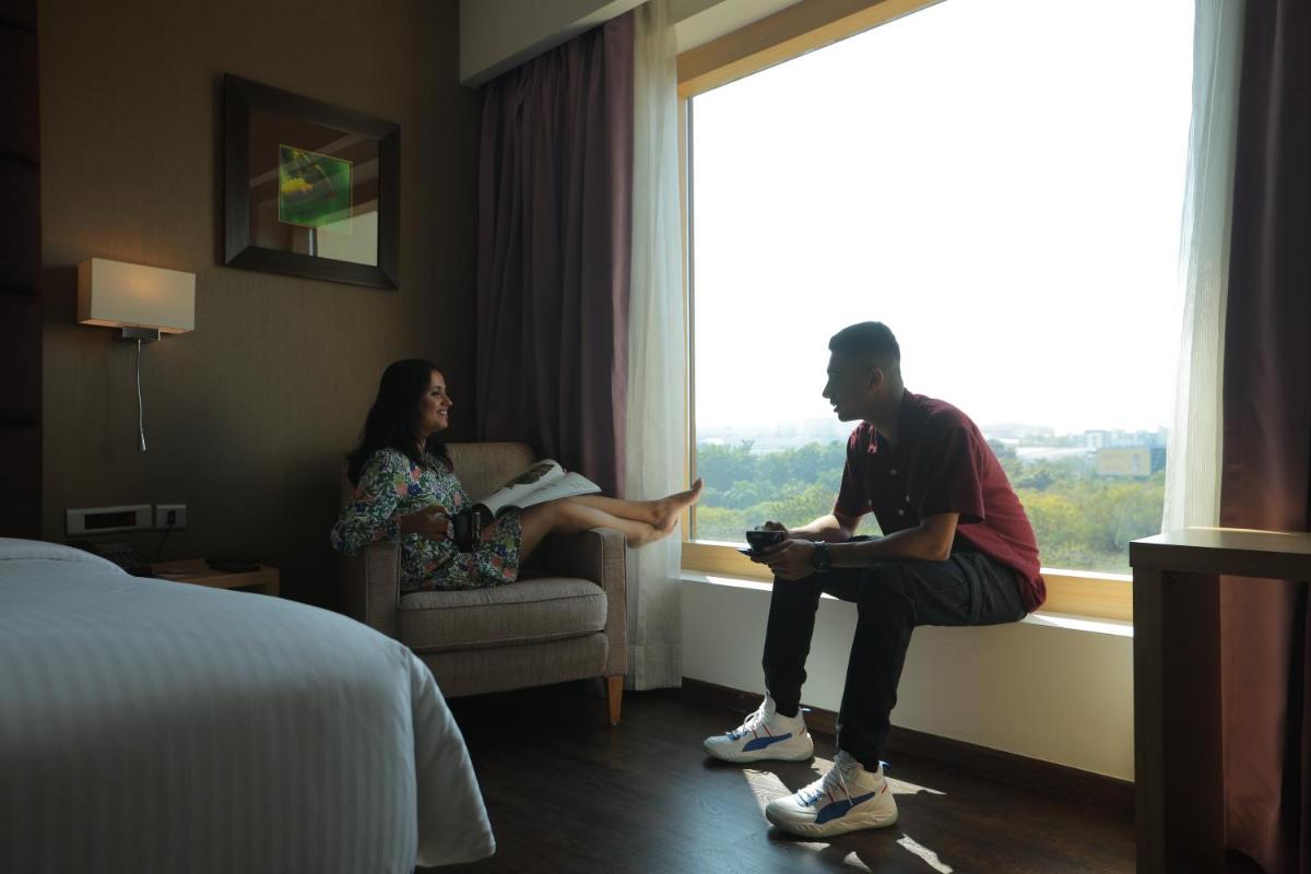 a man and woman sitting in a hotel room looking out the window at Novotel Hyderabad Airport in Hyderabad