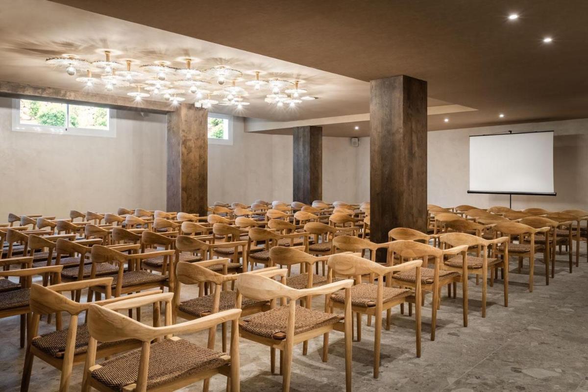 Una habitación con un montón de sillas y una pantalla. en Lago Resort Menorca - Suites del Lago Adults Only, en Cala'n Bosch