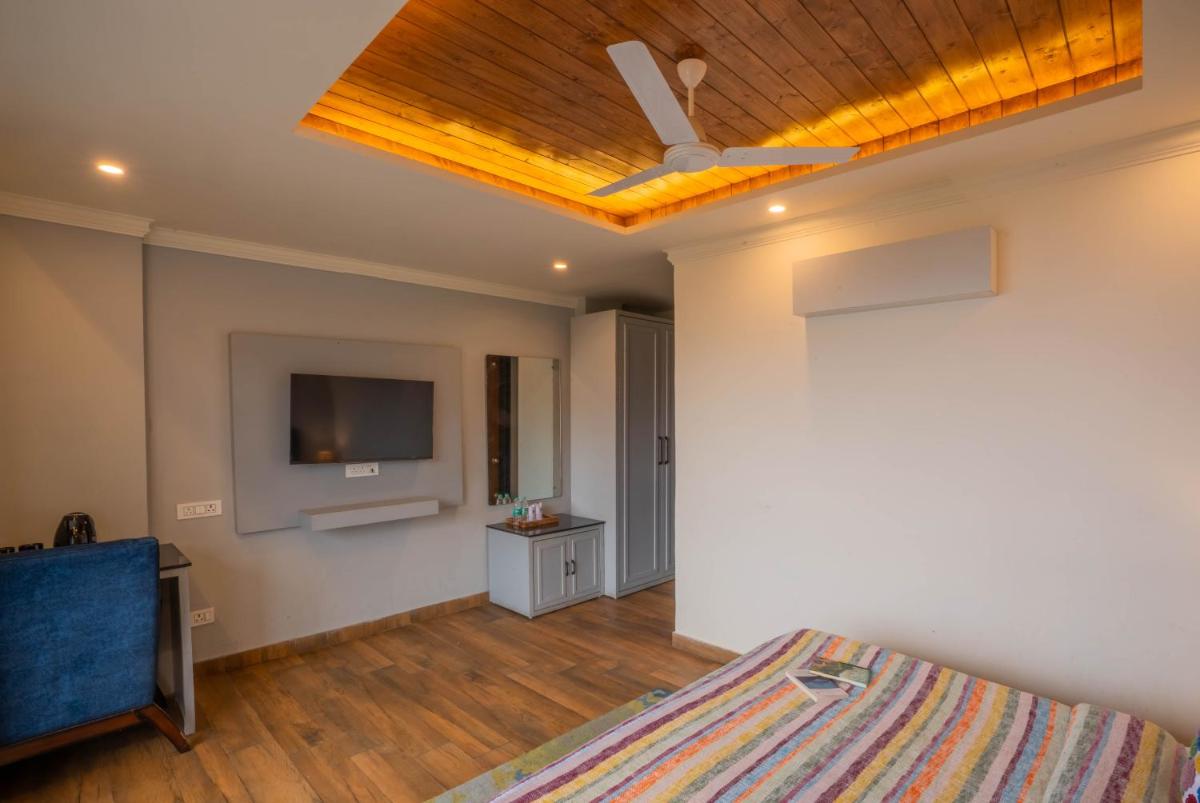 a bedroom with a ceiling fan and a tv at Perfectstayz Premium Westend at Mall Road in Mussoorie