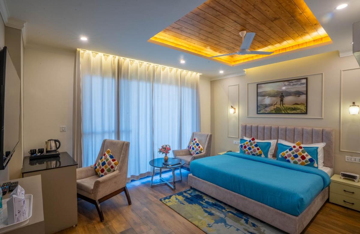 a bedroom with a blue bed and a table and chairs at Perfectstayz Premium Westend at Mall Road in Mussoorie
