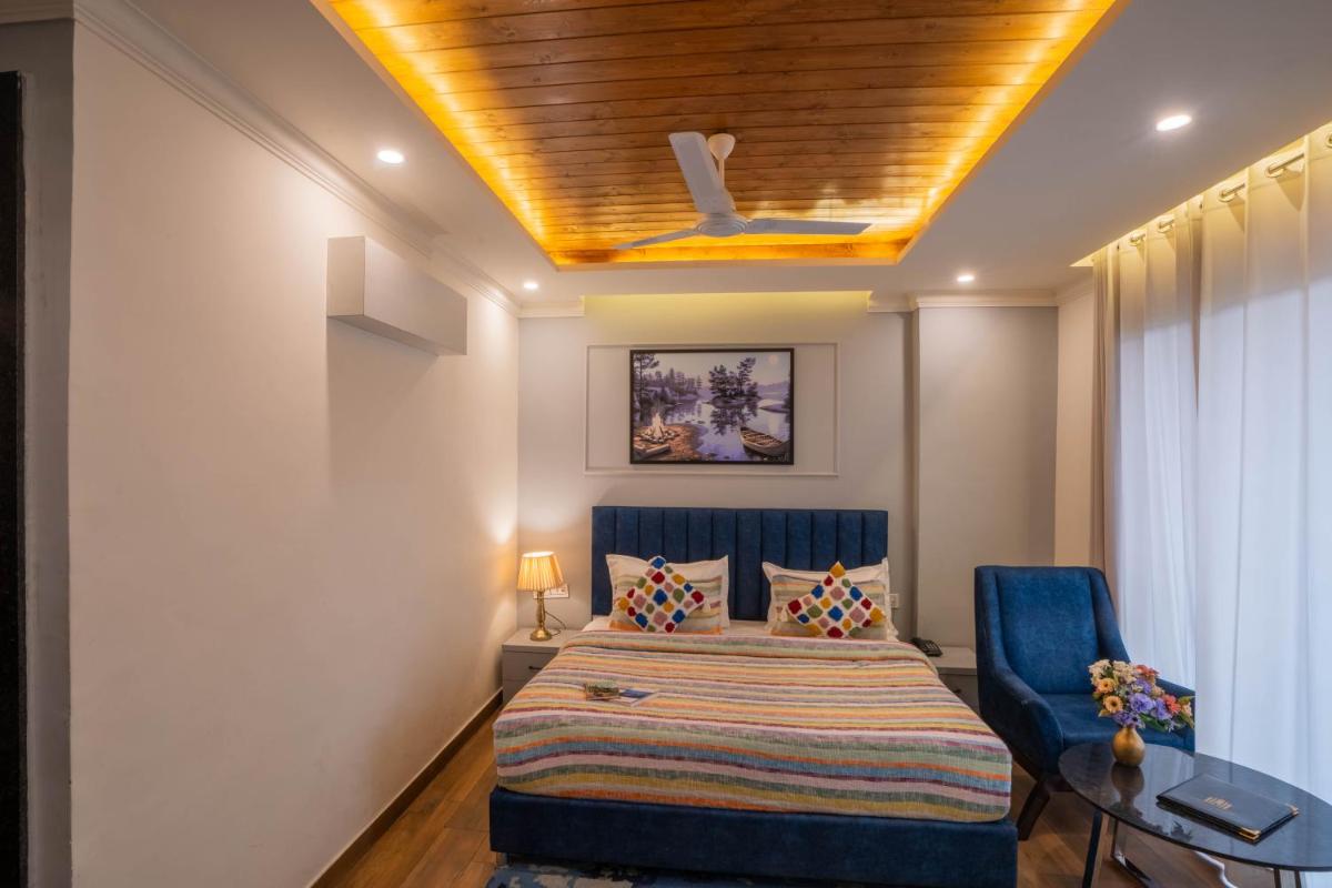 a bedroom with a bed and a blue chair at Perfectstayz Premium Westend at Mall Road in Mussoorie