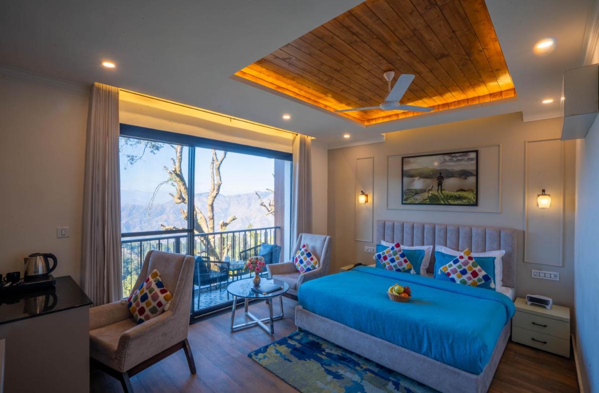 a bedroom with a blue bed and a balcony at Perfectstayz Premium Westend at Mall Road in Mussoorie