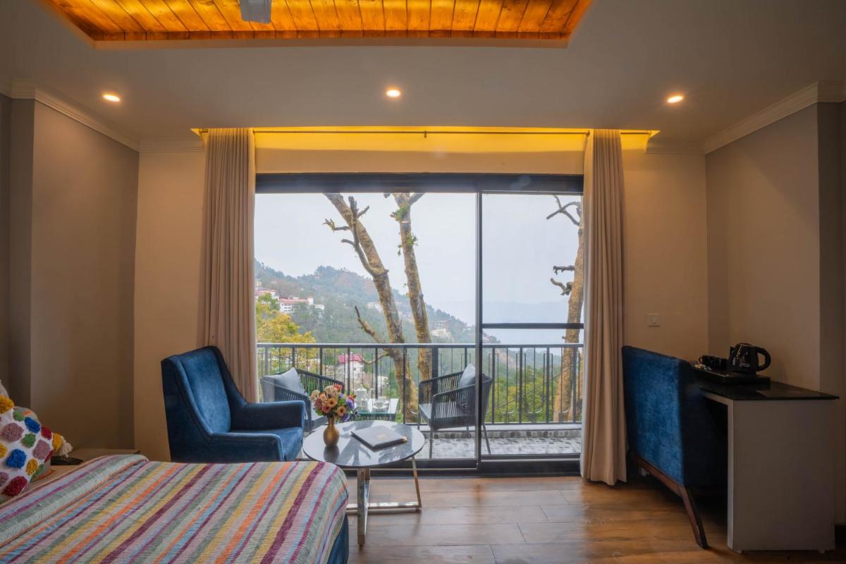 a bedroom with a bed and a balcony with a view at Perfectstayz Premium Westend at Mall Road in Mussoorie