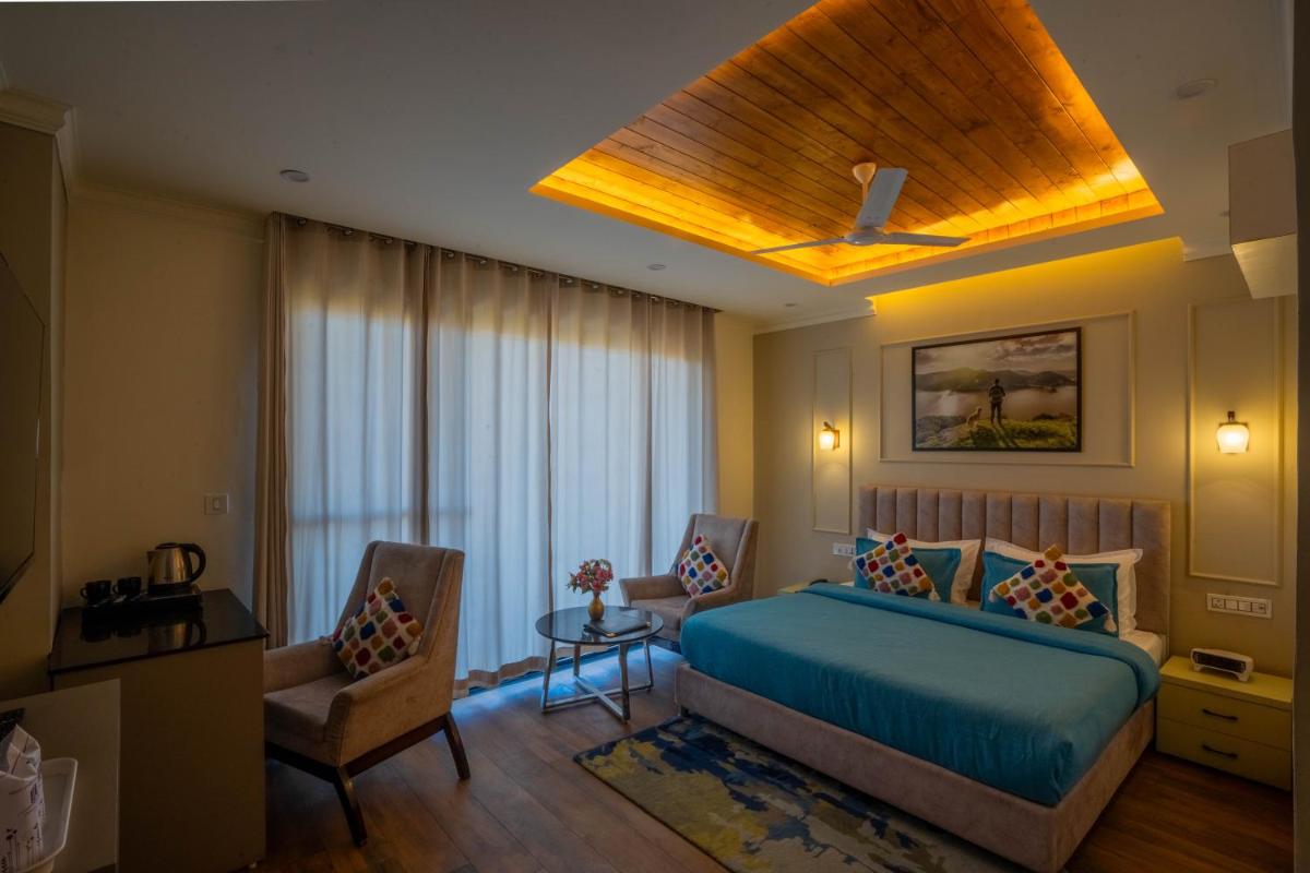 a bedroom with a blue bed and two chairs at Perfectstayz Premium Westend at Mall Road in Mussoorie +103 photos