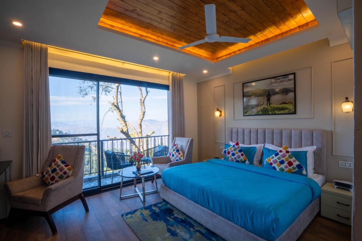 a bedroom with a blue bed and a balcony at Perfectstayz Premium Westend at Mall Road in Mussoorie