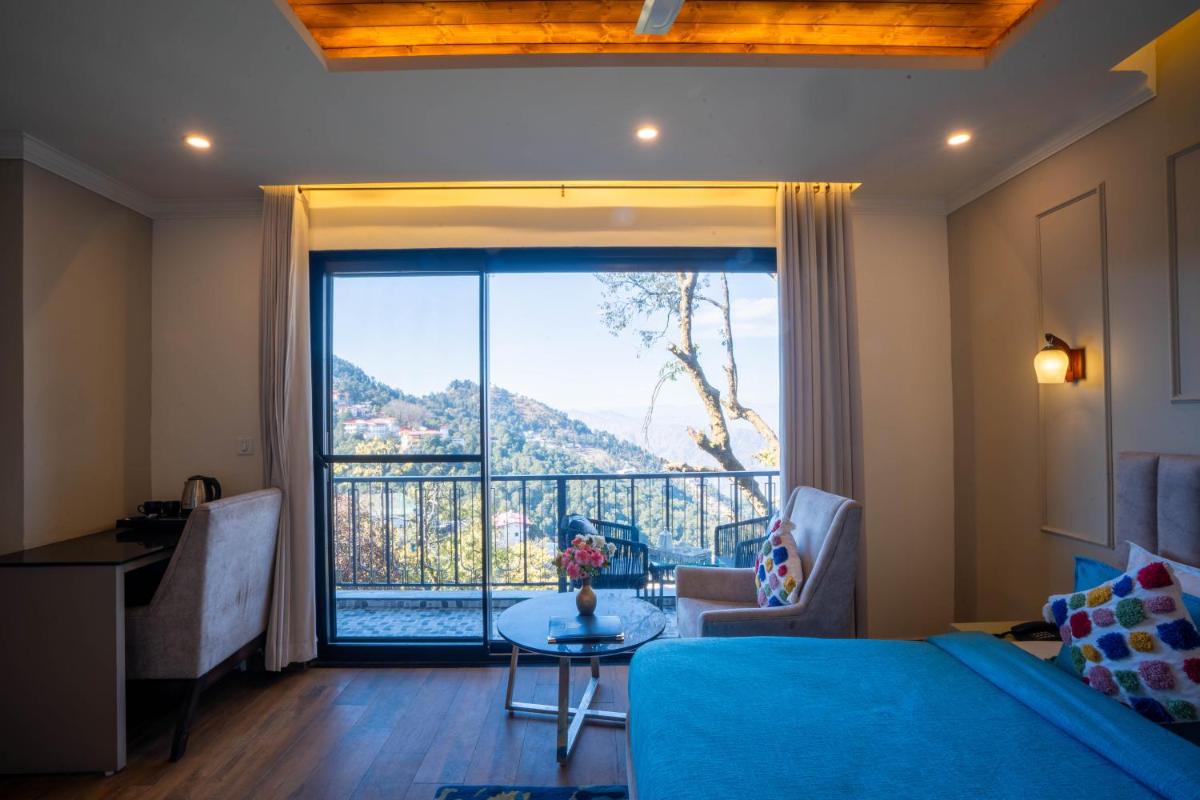 a living room with a blue couch and a large window at Perfectstayz Premium Westend at Mall Road in Mussoorie