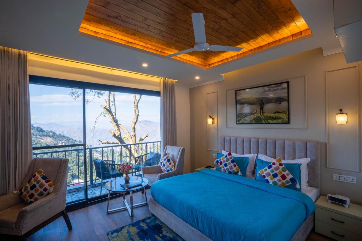 a bedroom with a blue bed and a balcony at Perfectstayz Premium Westend at Mall Road in Mussoorie