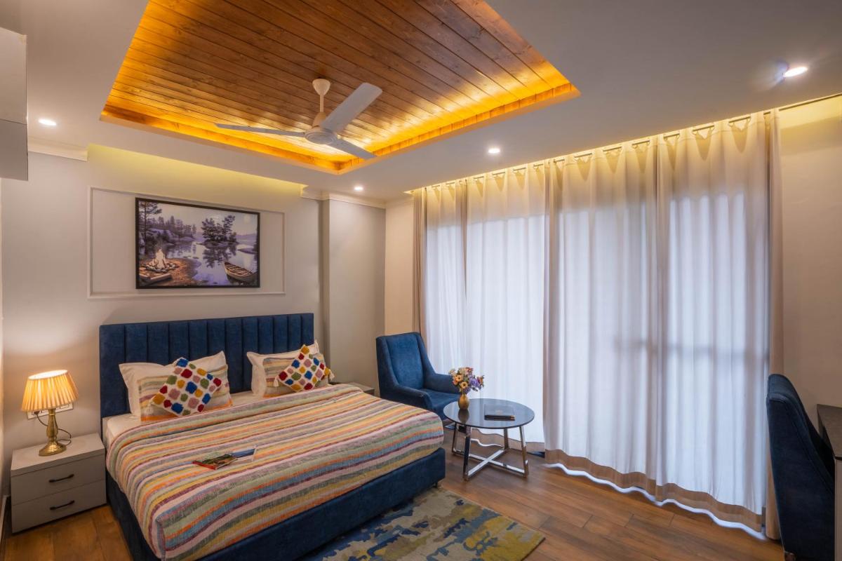 a bedroom with a bed and a chair and a window at Perfectstayz Premium Westend at Mall Road in Mussoorie
