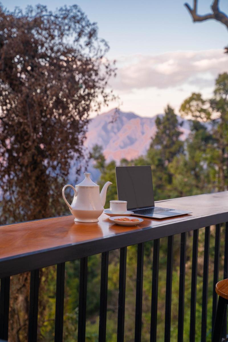 a table with a tea kettle and a laptop on a balcony at Perfectstayz Premium Westend at Mall Road in Mussoorie