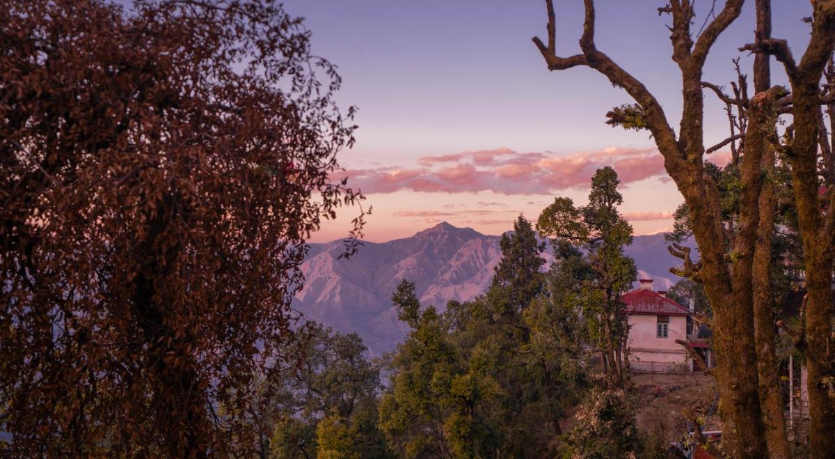 a house in the middle of trees with a mountain at Perfectstayz Premium Westend at Mall Road in Mussoorie