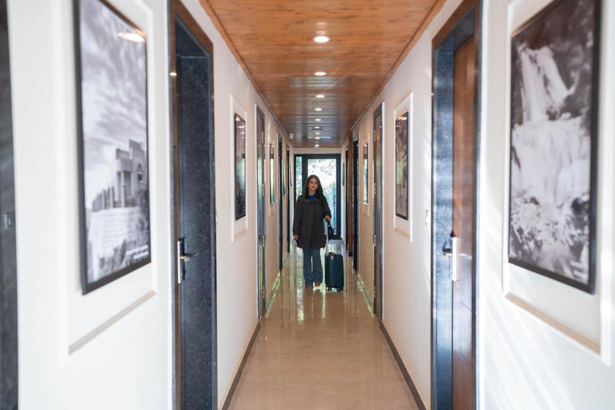a woman walking down a hallway with a suitcase at Perfectstayz Premium Westend at Mall Road in Mussoorie