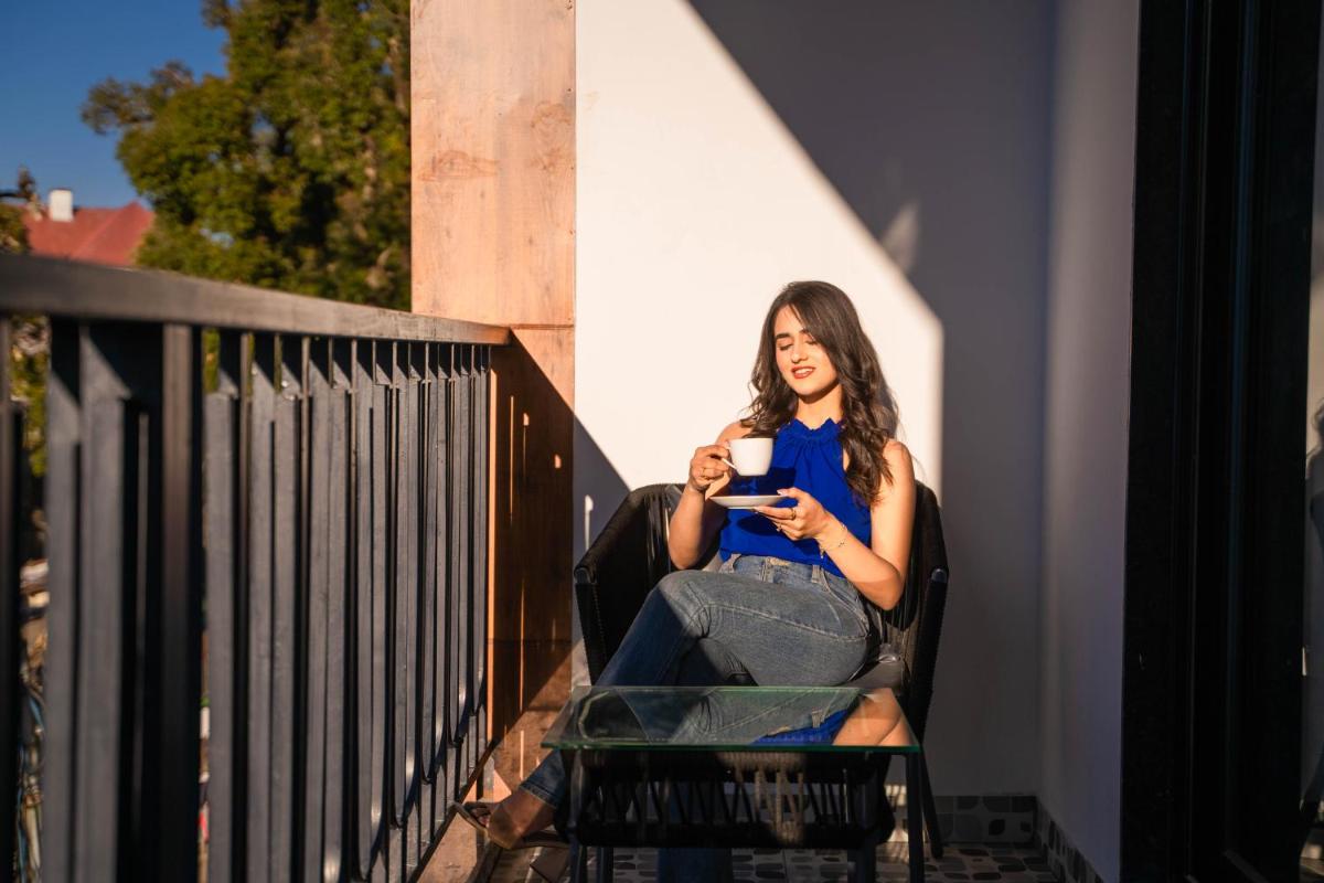 a woman sitting in a chair holding a cup of coffee at Perfectstayz Premium Westend at Mall Road in Mussoorie
