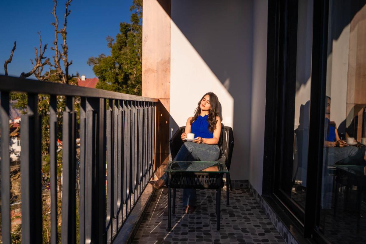 a woman sitting in a chair on a balcony at Perfectstayz Premium Westend at Mall Road in Mussoorie