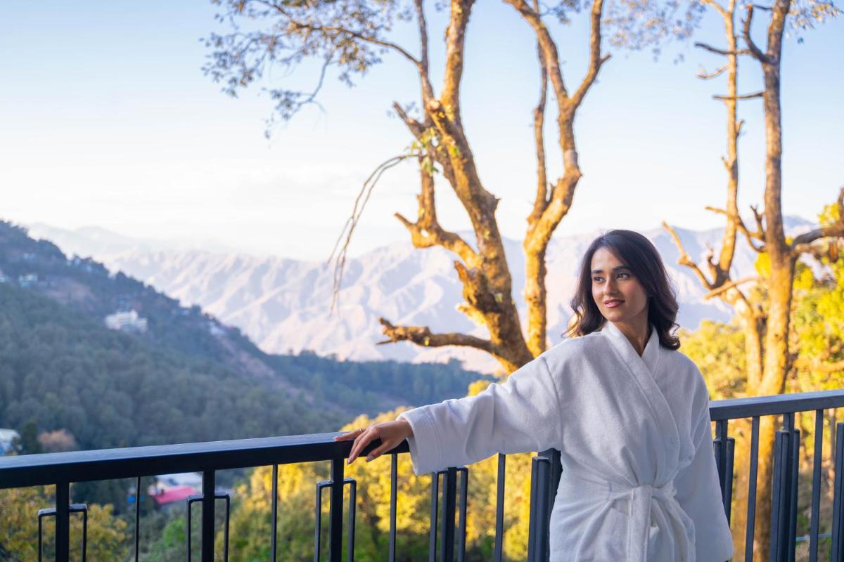 a woman in a white robe standing on a balcony at Perfectstayz Premium Westend at Mall Road in Mussoorie