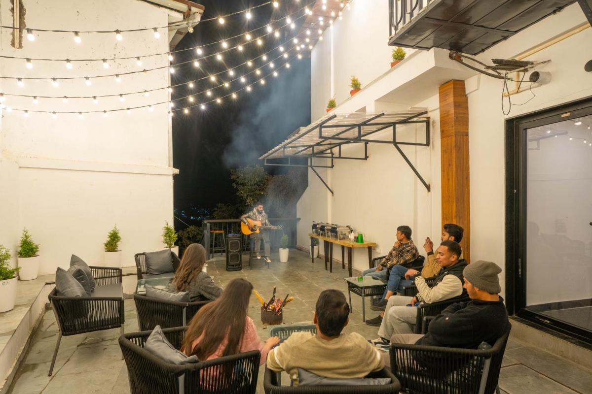 a group of people sitting in chairs in front of a fire at Perfectstayz Premium Westend at Mall Road in Mussoorie