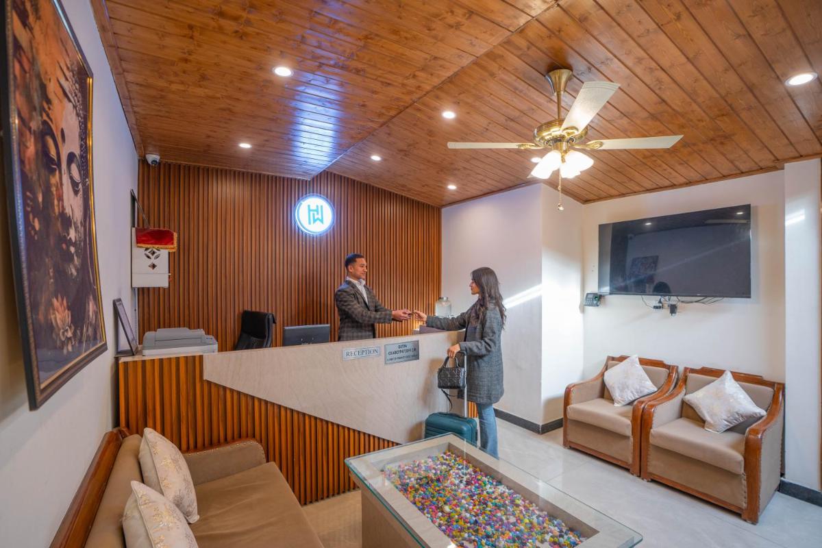 a man and woman standing at a counter in a waiting room at Perfectstayz Premium Westend at Mall Road in Mussoorie