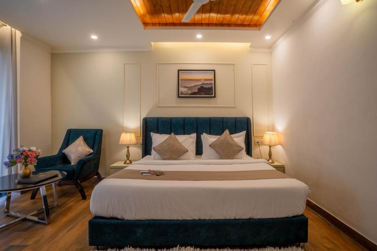 a bedroom with a large bed and two chairs at Perfectstayz Premium Westend at Mall Road in Mussoorie