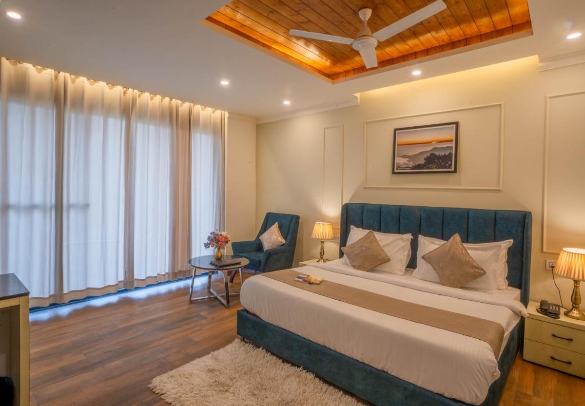 a bedroom with a bed and a chair in a room at Perfectstayz Premium Westend at Mall Road in Mussoorie