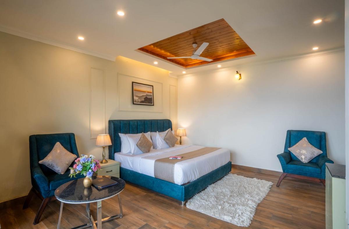a bedroom with a bed and two chairs and a table at Perfectstayz Premium Westend at Mall Road in Mussoorie
