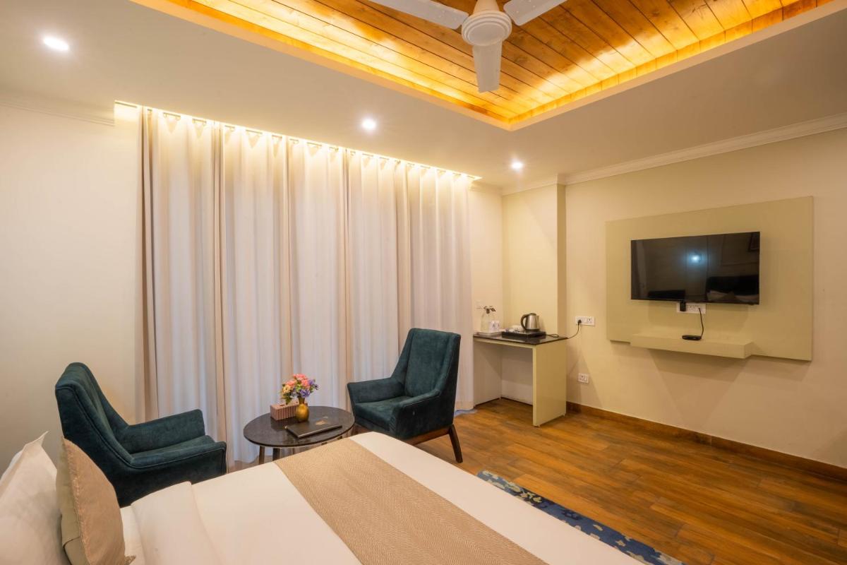 a hotel room with a bed and two chairs and a tv at Perfectstayz Premium Westend at Mall Road in Mussoorie