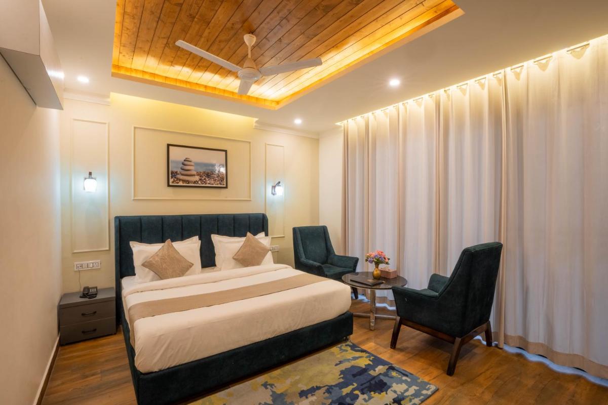 a hotel room with a bed and two chairs at Perfectstayz Premium Westend at Mall Road in Mussoorie