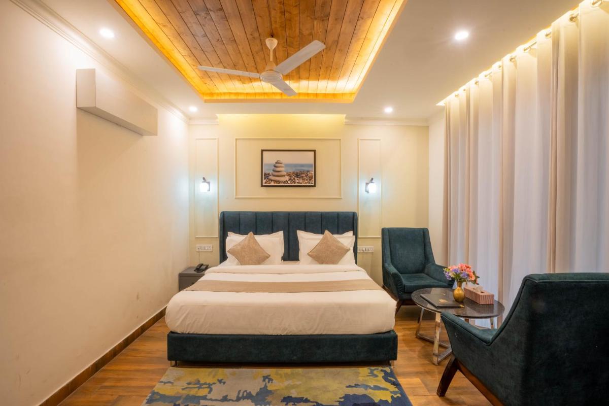 a hotel room with a bed and two chairs at Perfectstayz Premium Westend at Mall Road in Mussoorie