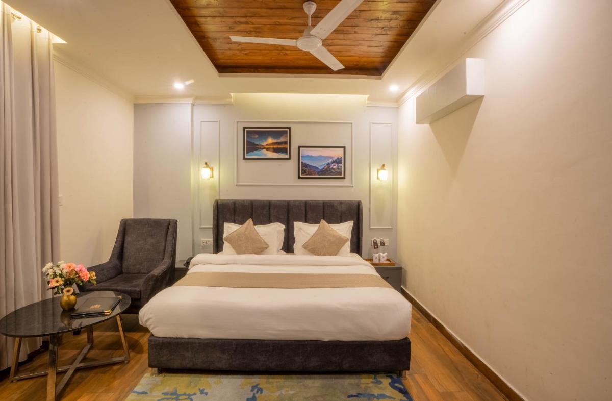 a bedroom with a bed and a chair and a table at Perfectstayz Premium Westend at Mall Road in Mussoorie