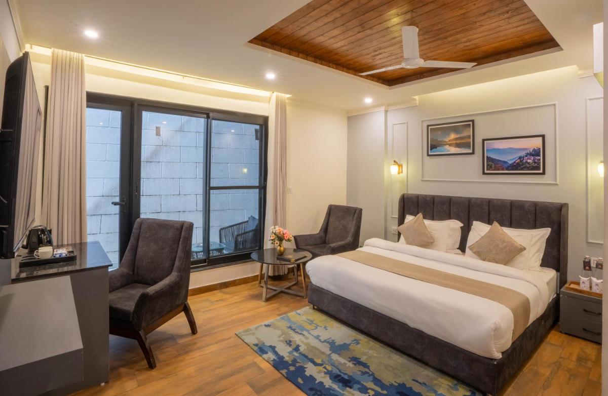 a hotel room with a bed and a desk and chairs at Perfectstayz Premium Westend at Mall Road in Mussoorie