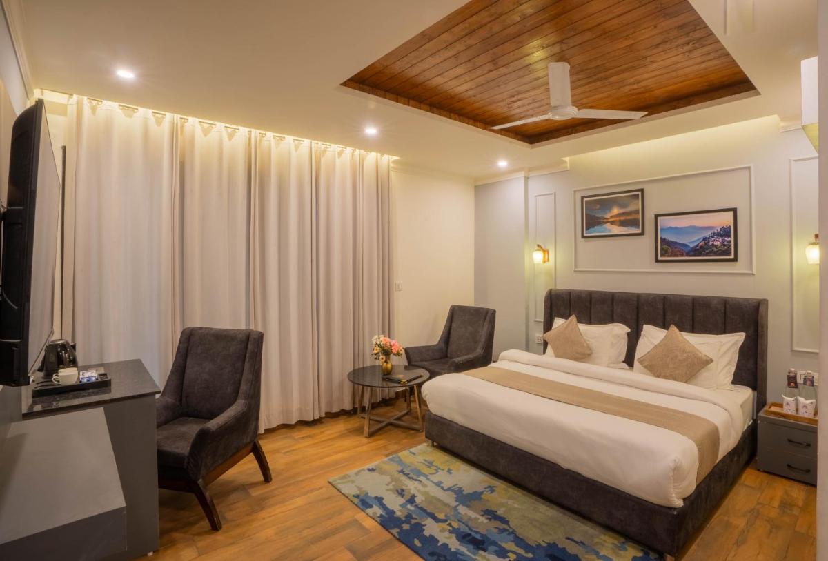 a bedroom with a bed and two chairs and a desk at Perfectstayz Premium Westend at Mall Road in Mussoorie