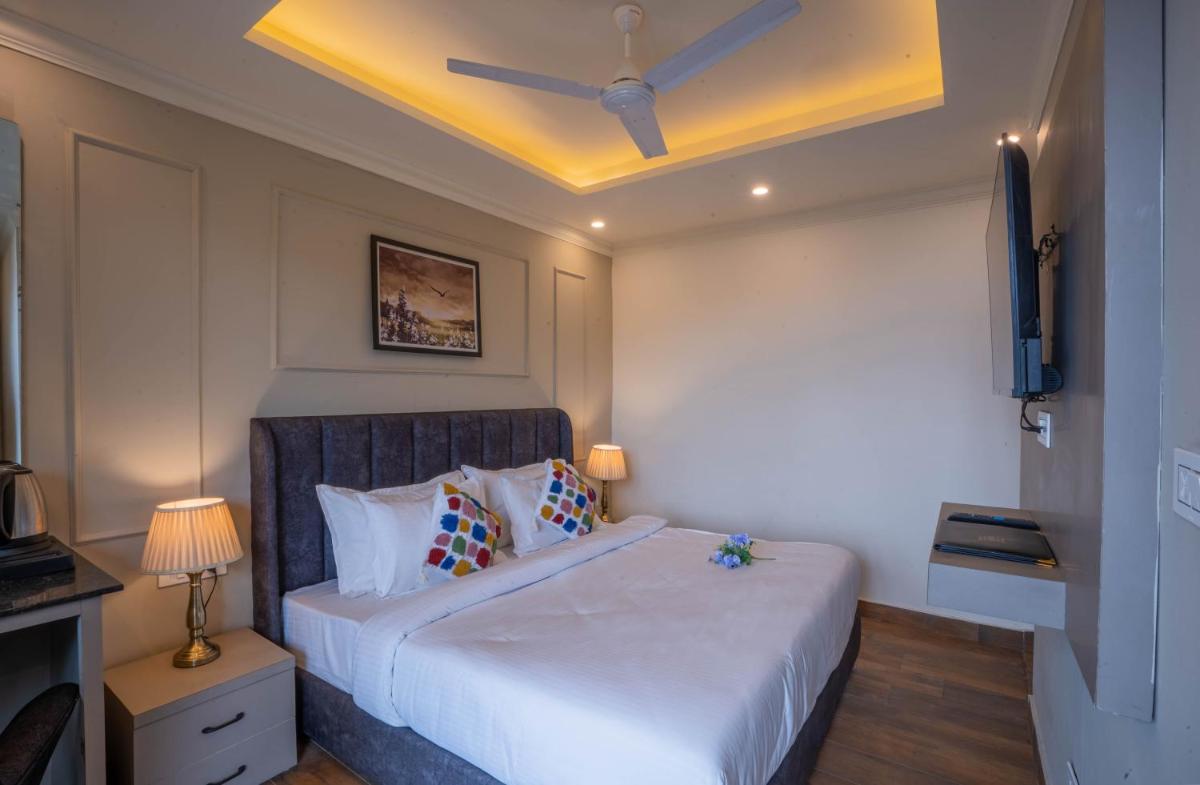 a bedroom with a large white bed with a ceiling at Perfectstayz Premium Westend at Mall Road in Mussoorie