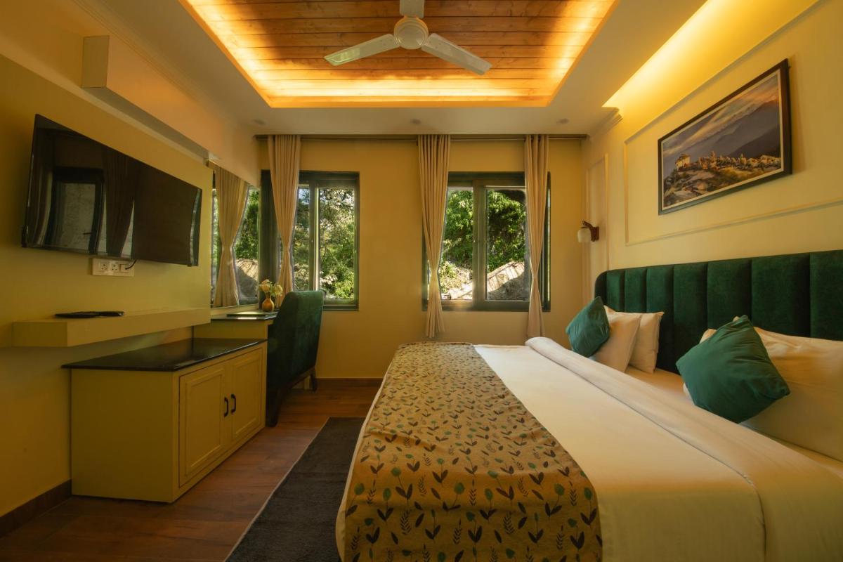 a bedroom with a large bed with a ceiling fan at Perfectstayz Premium Westend at Mall Road in Mussoorie