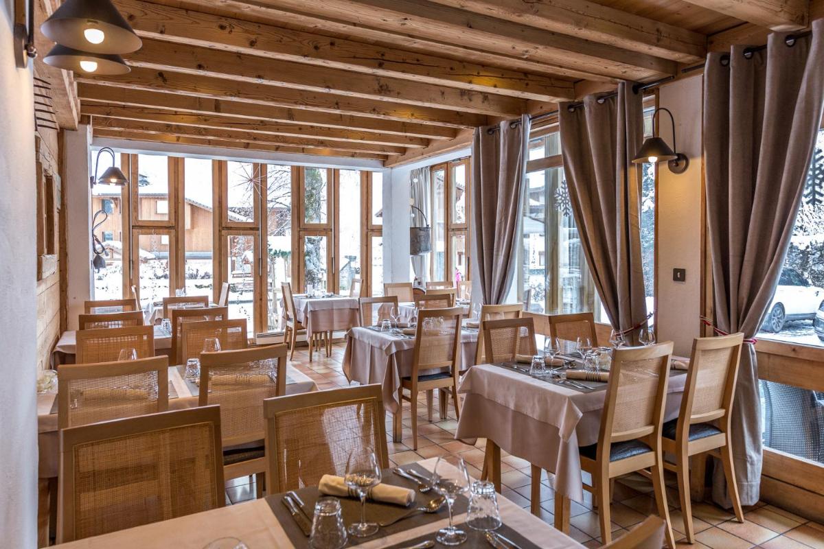 un restaurant avec des tables, des chaises et des fenêtres dans l'établissement Logis Hotel Gai Soleil, à Samoëns