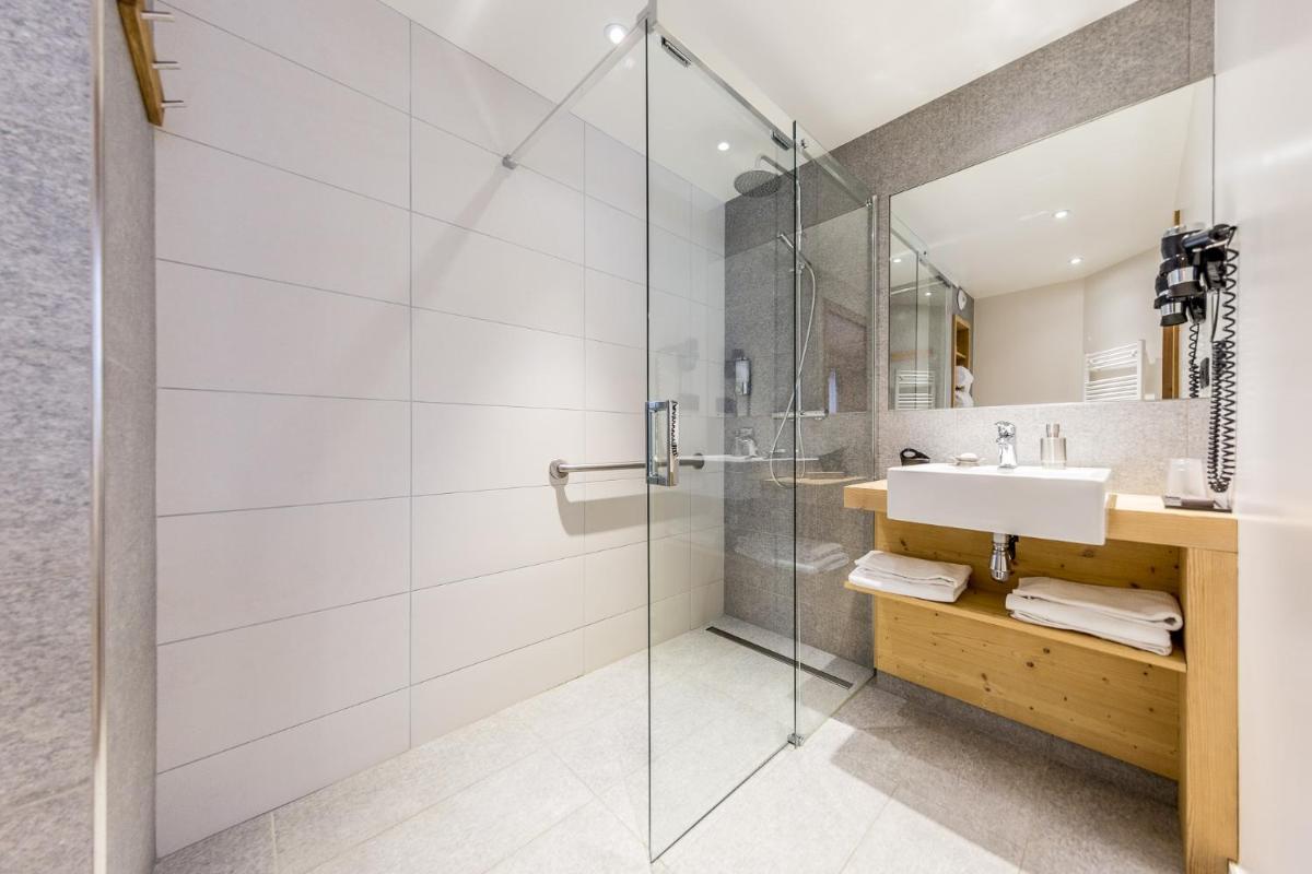 une salle de bain avec une douche en verre et un lavabo dans l'établissement Logis Hotel Gai Soleil, à Samoëns