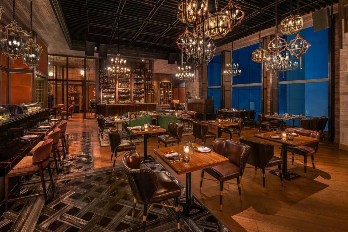 a restaurant with tables and chairs and chandeliers at The St. Regis Mumbai in Mumbai