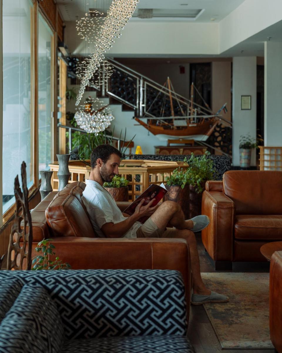 a man sitting on a couch reading a book at The Panoramic Getaway in Munnar