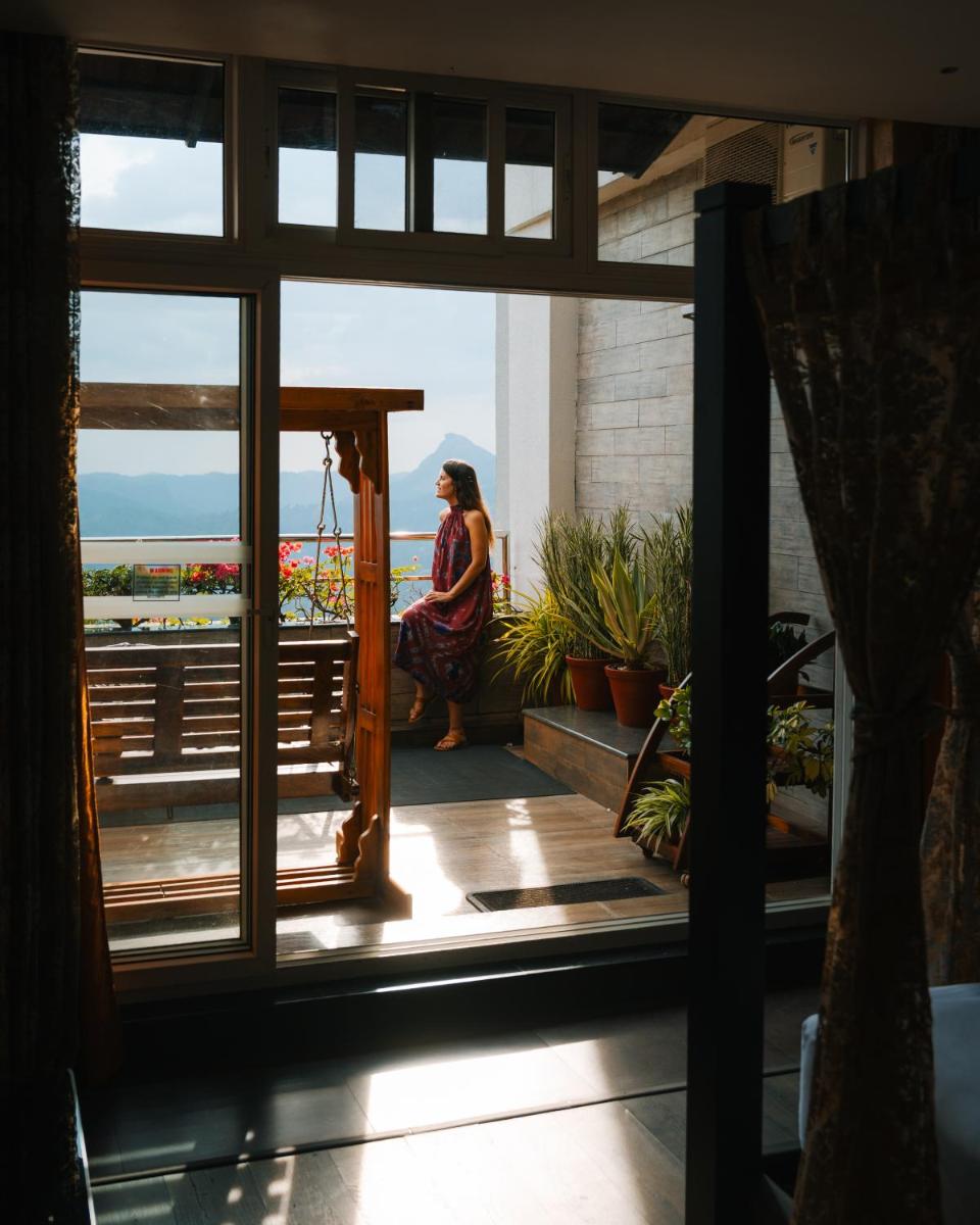 a woman sitting on a balcony looking out at the ocean at The Panoramic Getaway in Munnar