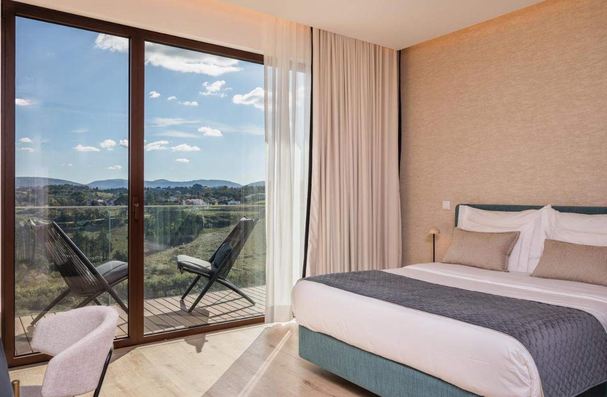 um quarto com uma cama e uma varanda com vista em Haven Nature Hotel & Villas na Batalha