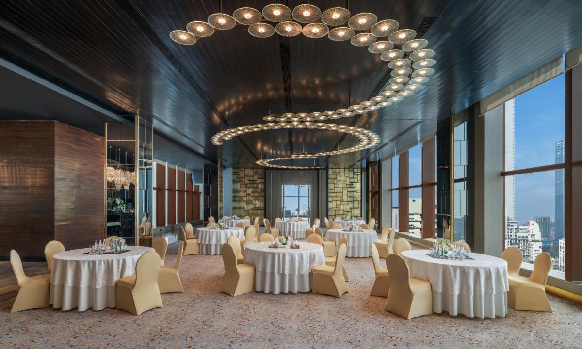 a dining room with tables and chairs and a chandelier at The St. Regis Mumbai in Mumbai