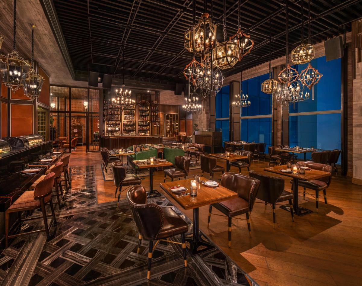 a restaurant with tables and chairs and chandeliers at The St. Regis Mumbai in Mumbai