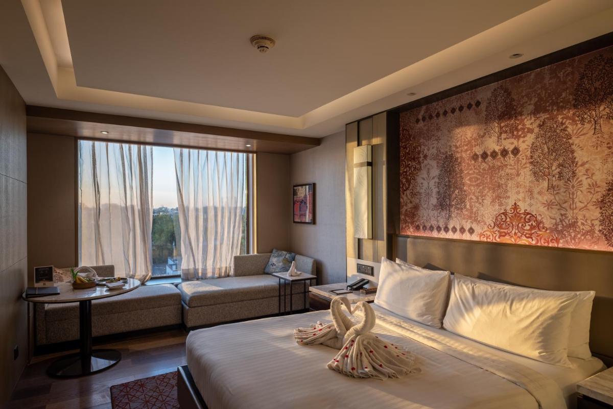 a hotel room with a bed and a living room at Courtyard by Marriott Amritsar in Amritsar