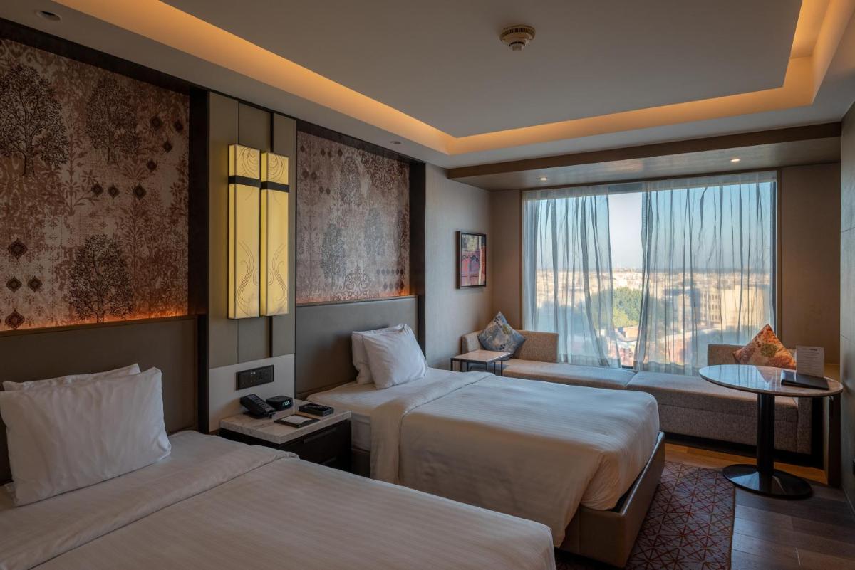 a hotel room with two beds and a window at Courtyard by Marriott Amritsar in Amritsar