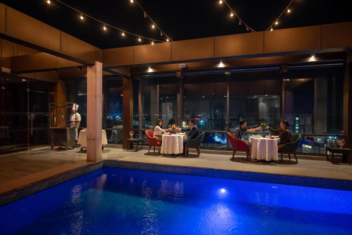 a group of people sitting at tables next to a pool at Courtyard by Marriott Amritsar in Amritsar