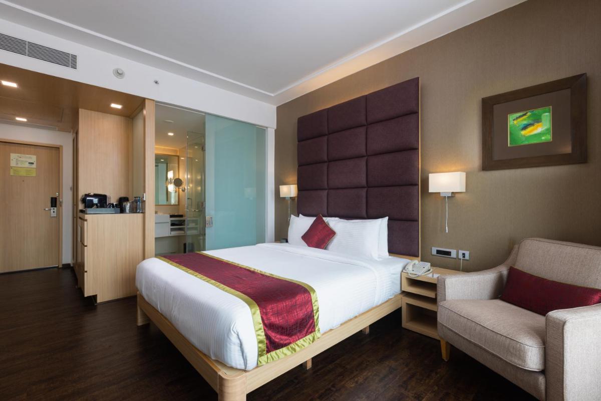 a bedroom with a large bed and a chair in it at Novotel Hyderabad Airport in Hyderabad