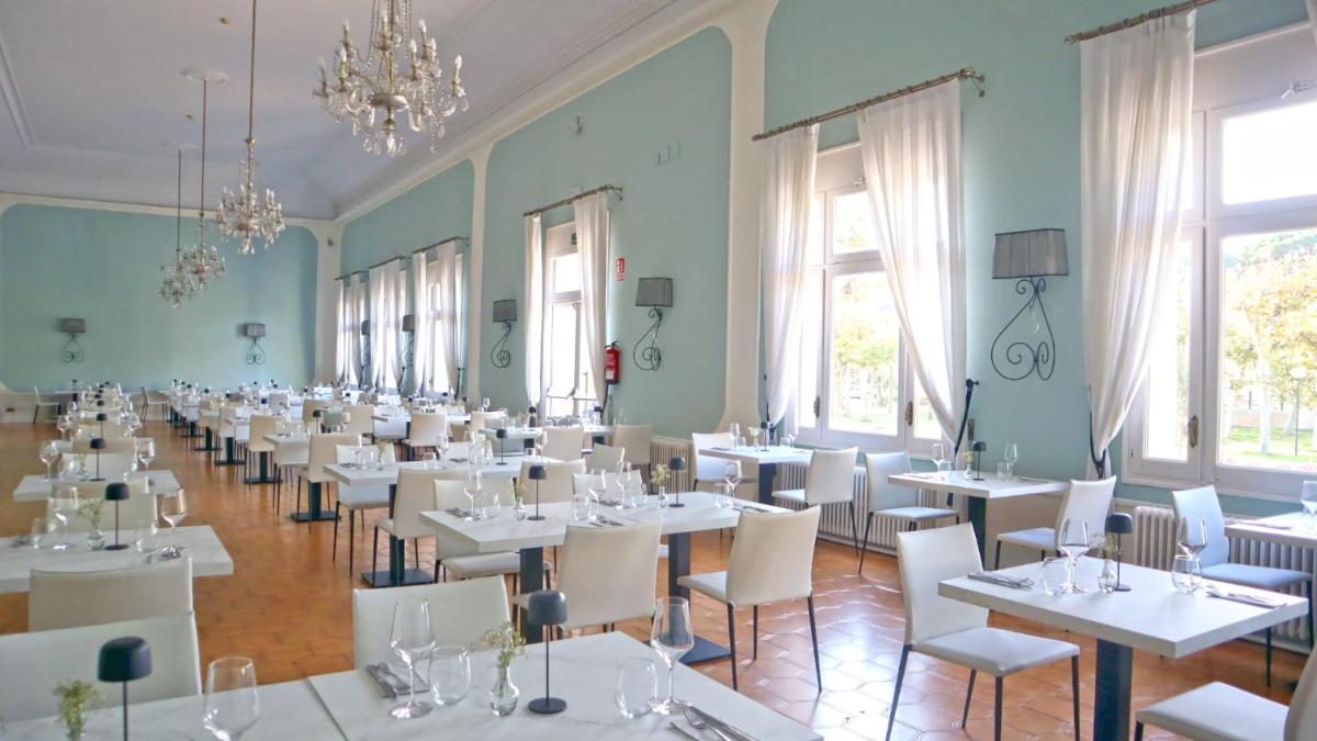 Un comedor con mesas blancas y sillas blancas. en 1881 Hotel Balneario Vichy Catalan, en Caldes de Malavella