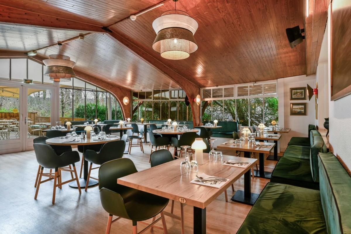 un restaurant avec des plafonds en bois, des tables et des chaises dans l'établissement Logis Thermal, à Saubusse