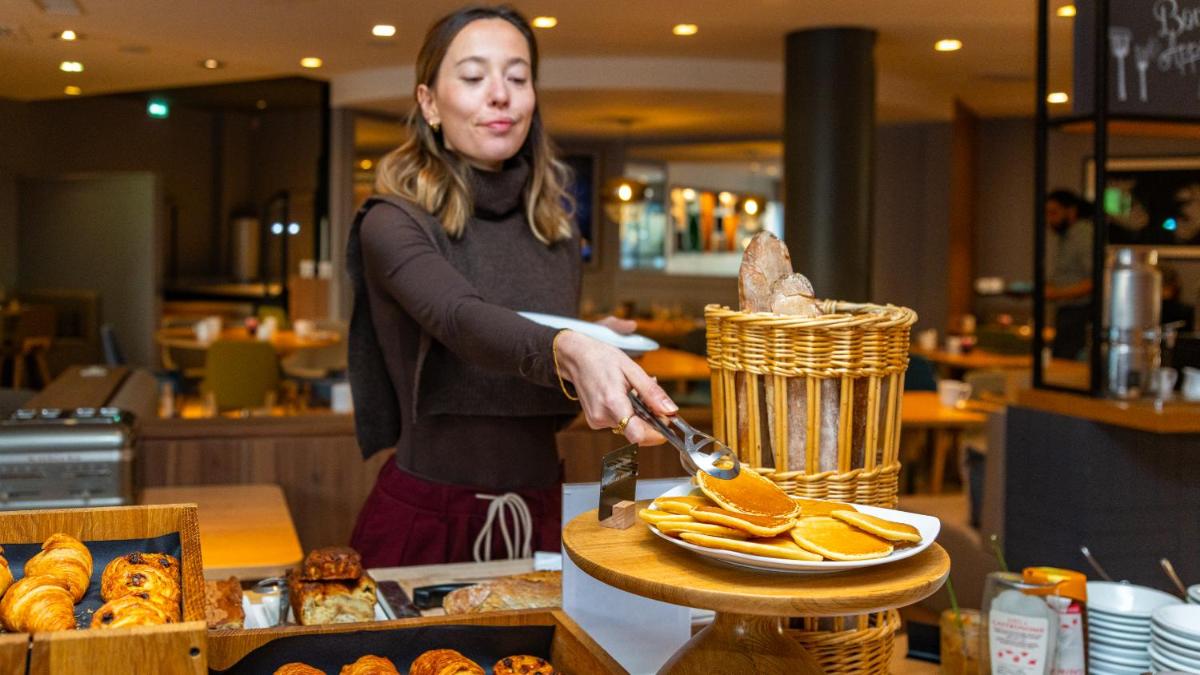 une femme sert de la nourriture dans une boulangerie dans l'établissement Holiday Inn Dijon Toison D'or by IHG, à Dijon 140 autres photos