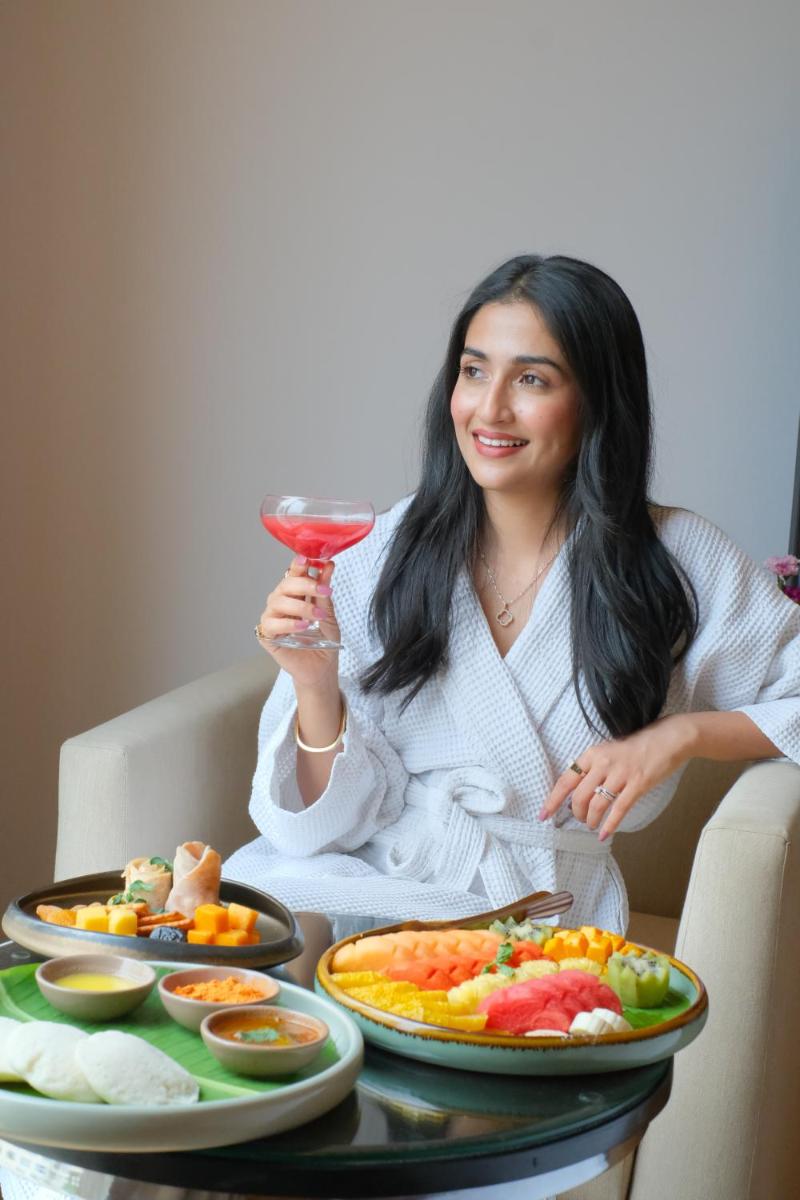 a woman sitting at a table with a drink at Courtyard by Marriott Bengaluru Outer Ring Road in Bengaluru