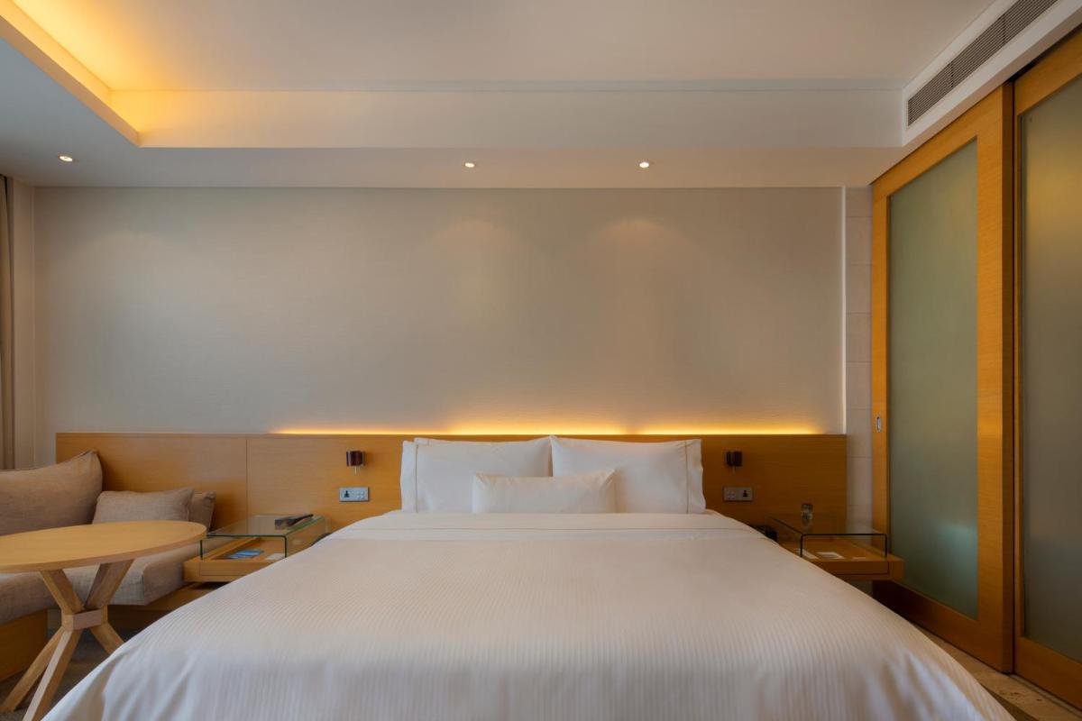 a bedroom with a large white bed and a table at The Westin Mumbai Garden City in Mumbai